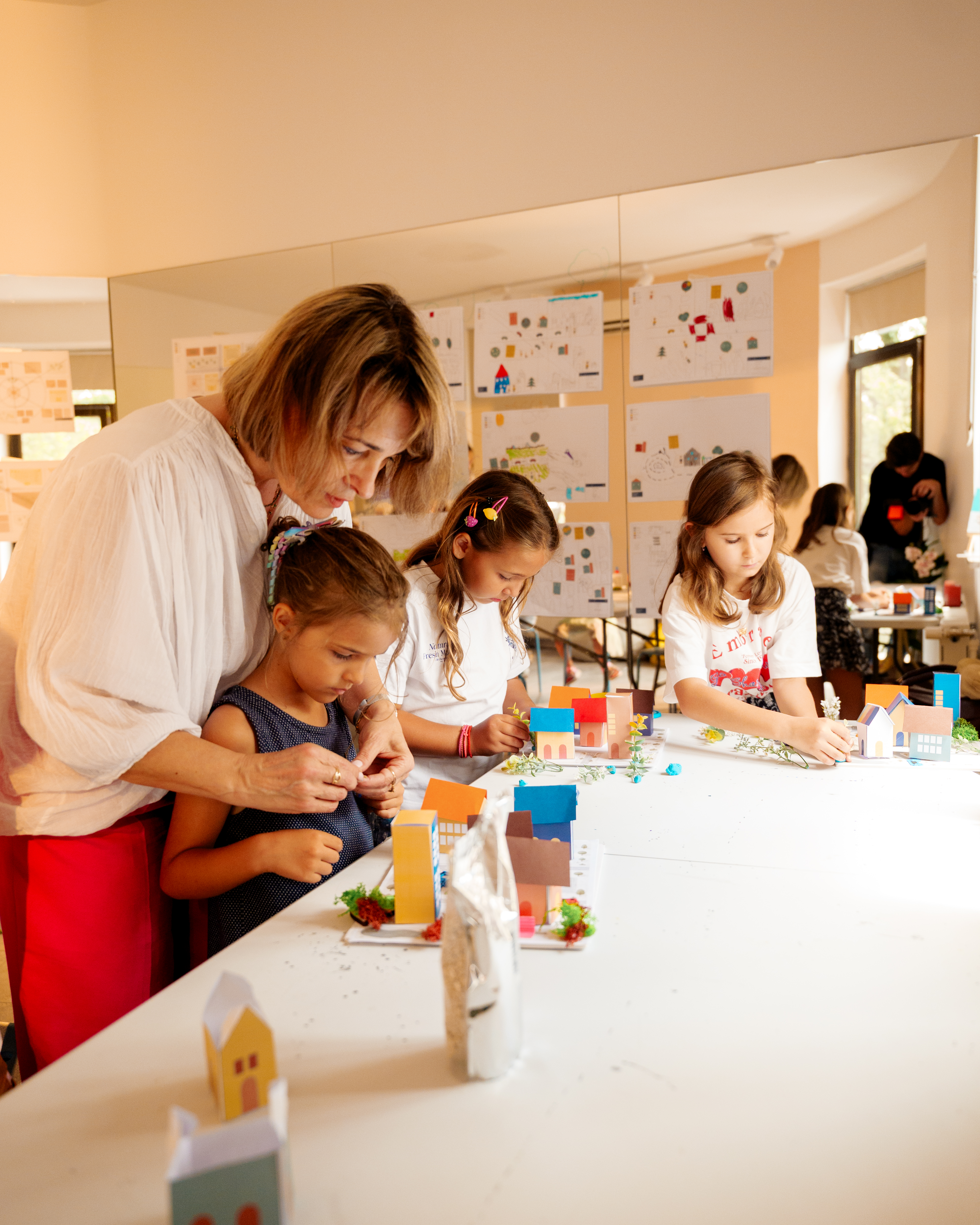 Trei copii privesc turnul construit la atelier, lângă rollup-ul studioului